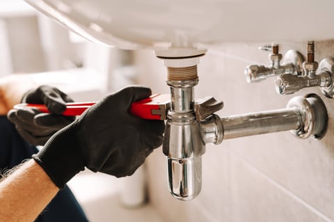 Plumber fixing sink pipe with wrench