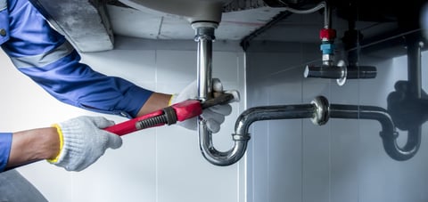 Plumber repairing sink and clogged pipe